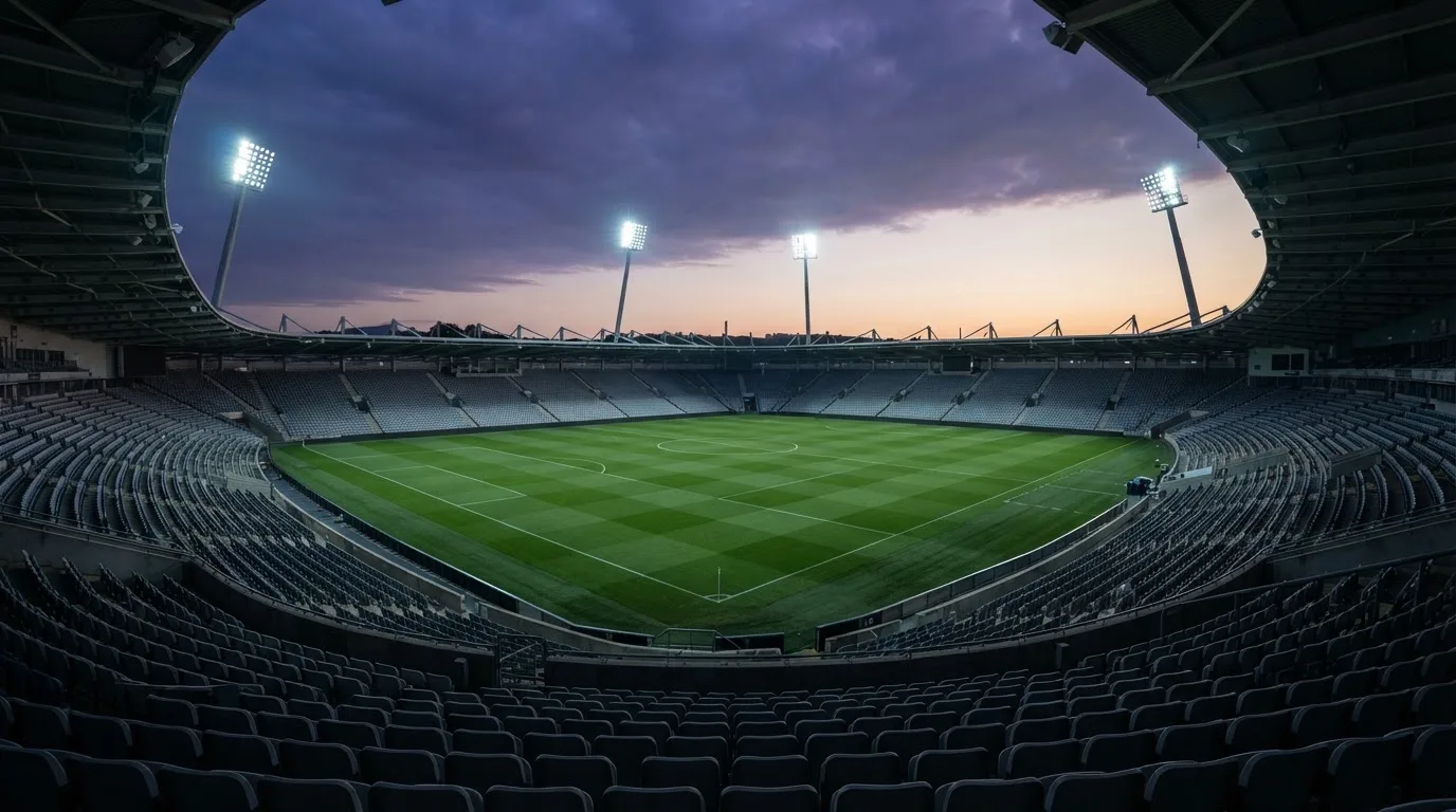 An empty football stadium with floodlight masts at dusk
