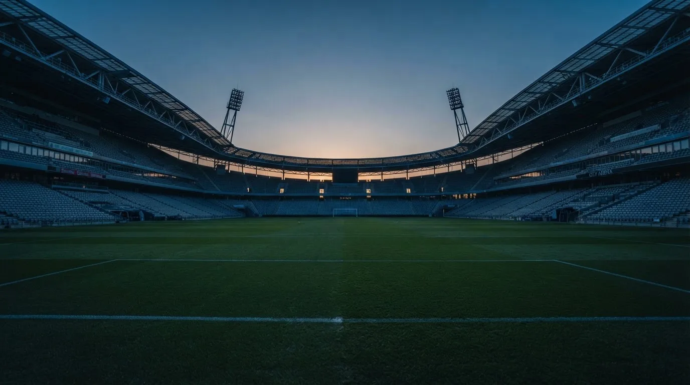 An empty football stadium with floodlight masts at dusk
