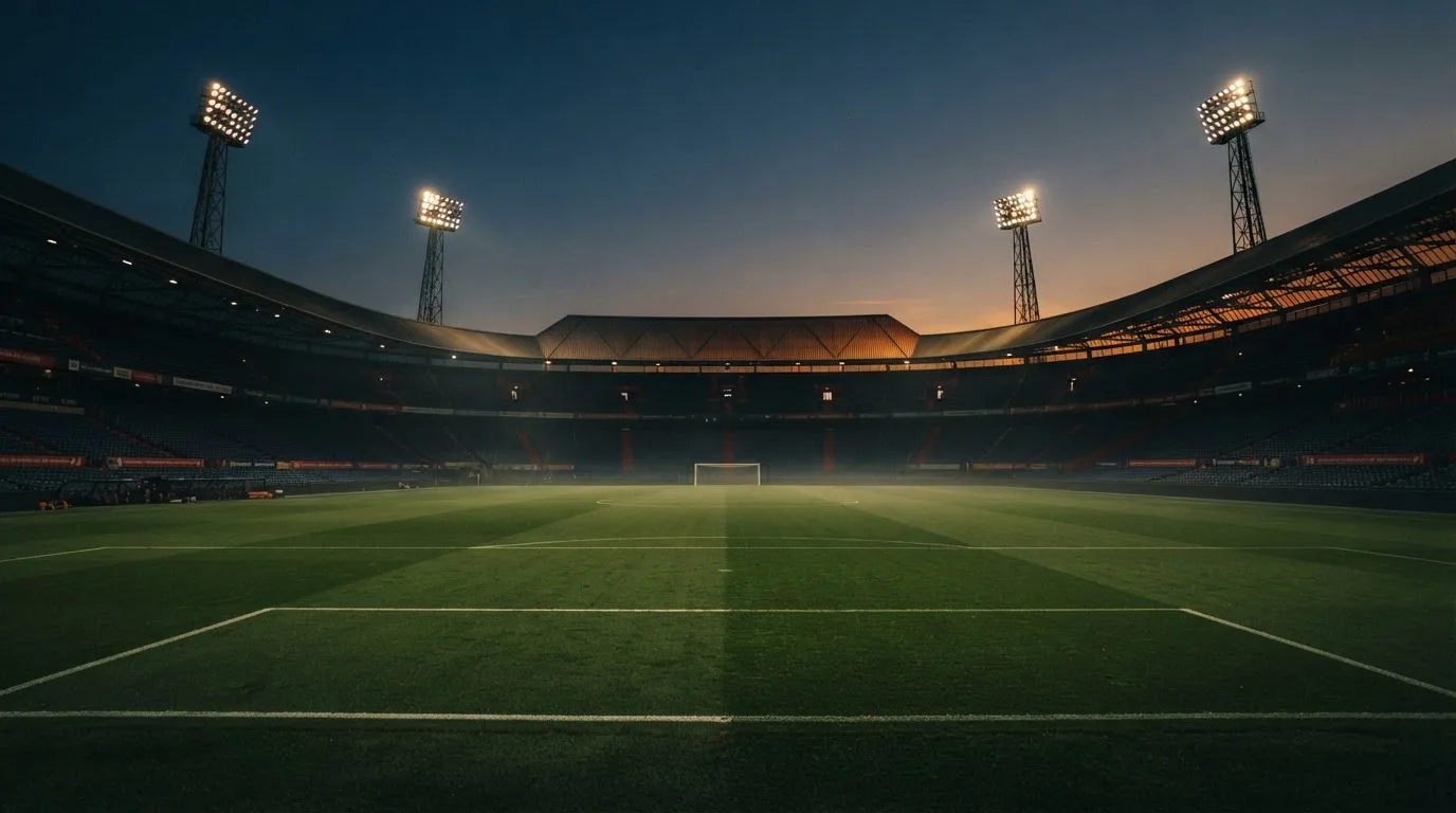 An empty football stadium with floodlight masts at dusk