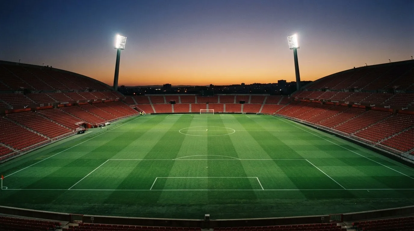 An empty football stadium with floodlight masts at dusk