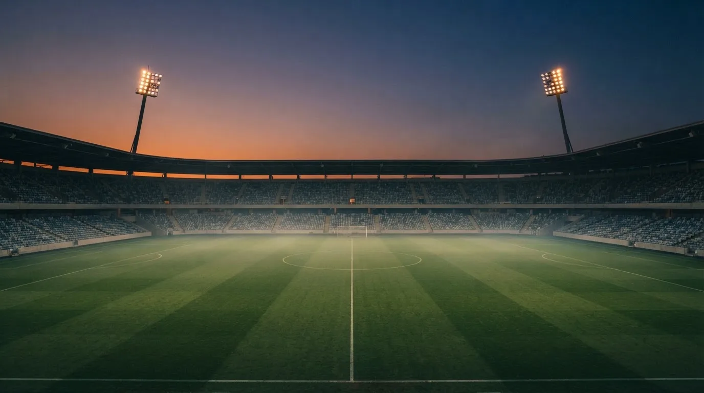 An empty football stadium with floodlight masts at dusk