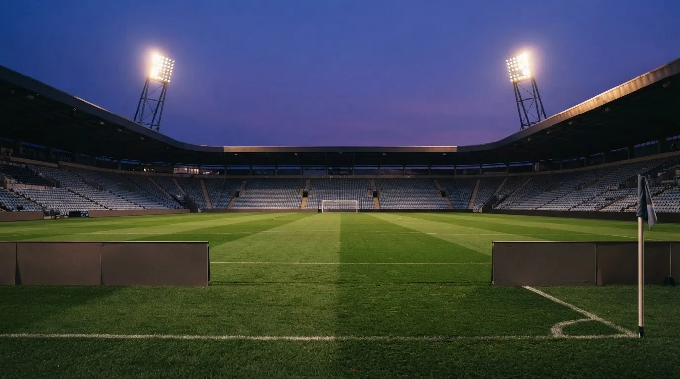 An empty football stadium with floodlight masts at dusk
