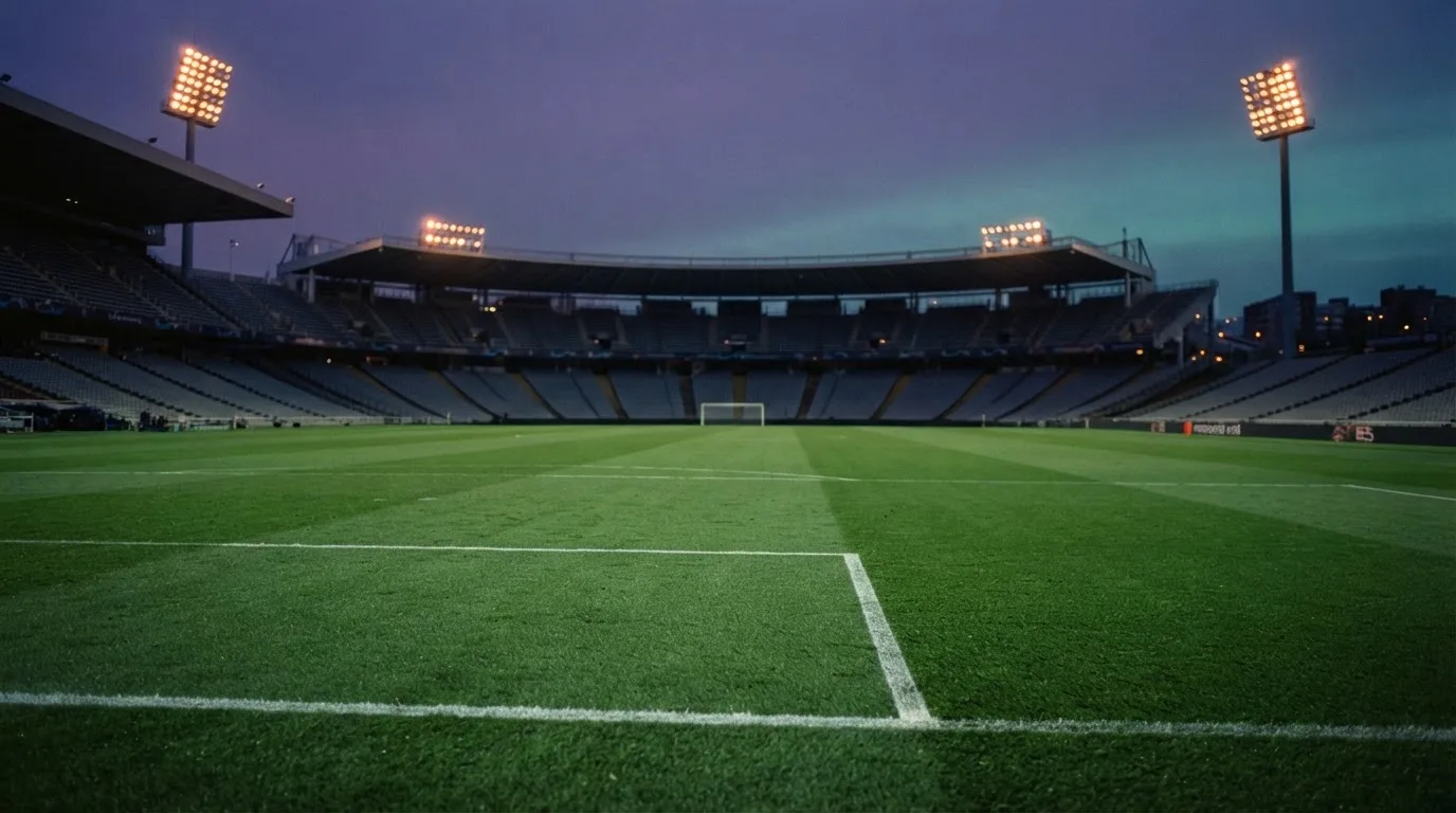 An empty football stadium with floodlight masts at dusk