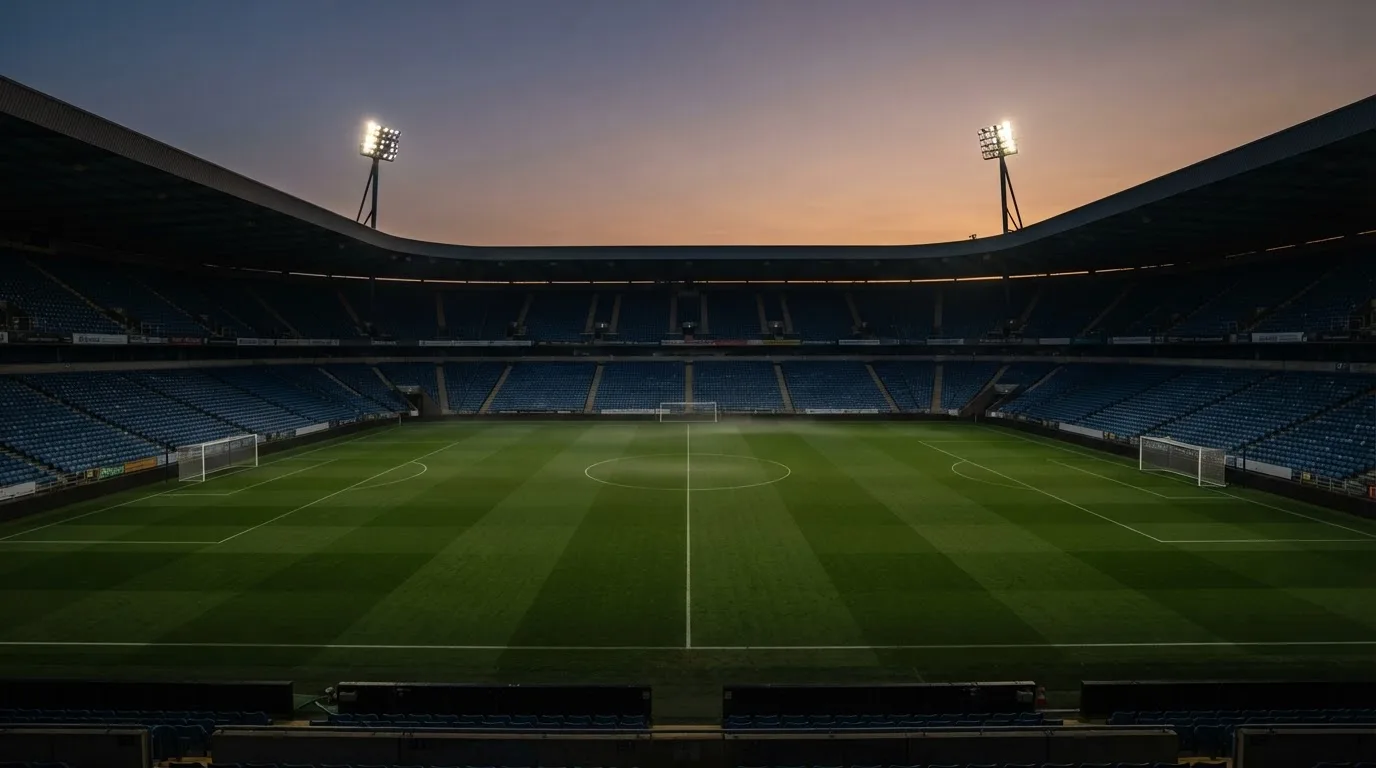 An empty football stadium with floodlight masts at dusk