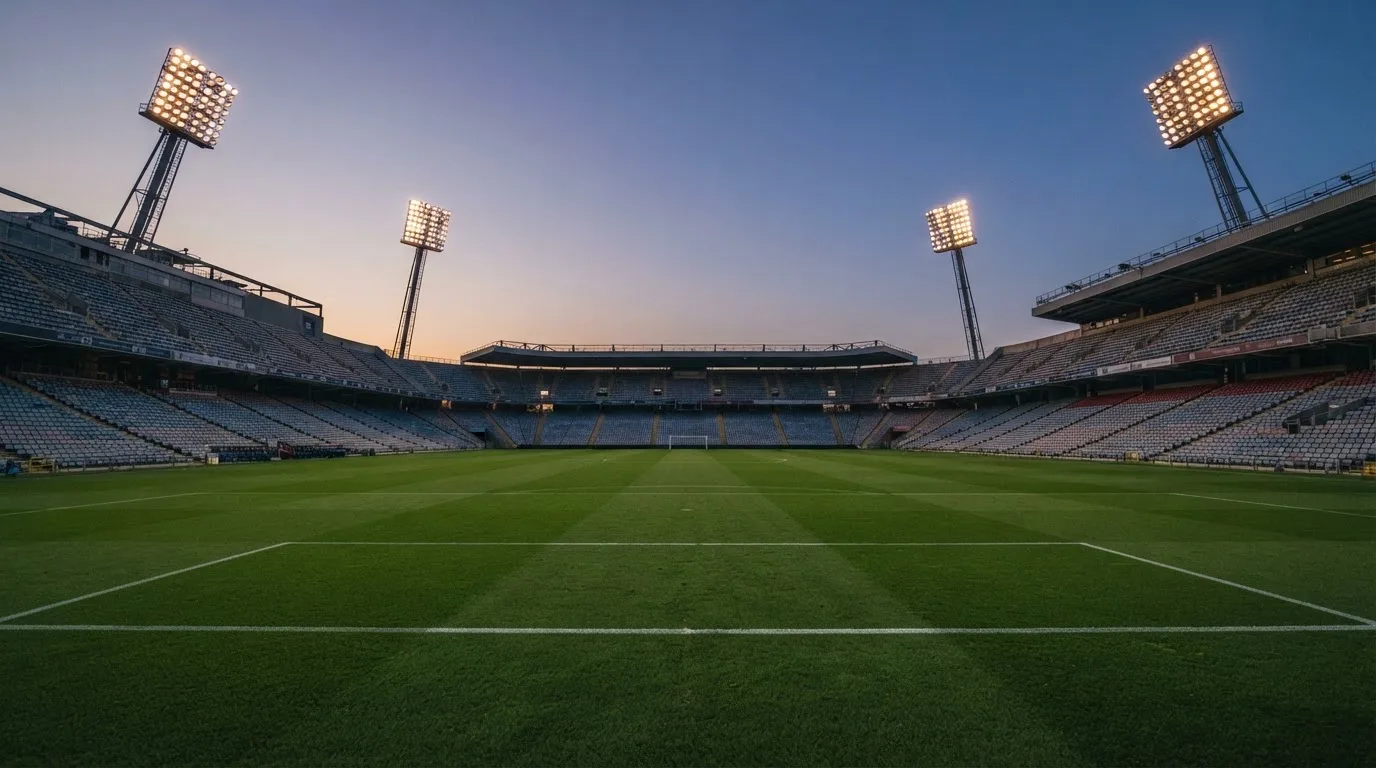 An empty football stadium with floodlight masts at dusk