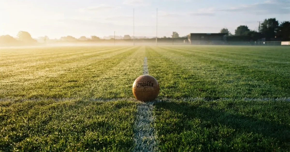 A ball on the centre spot of a grass pitch in morning light
