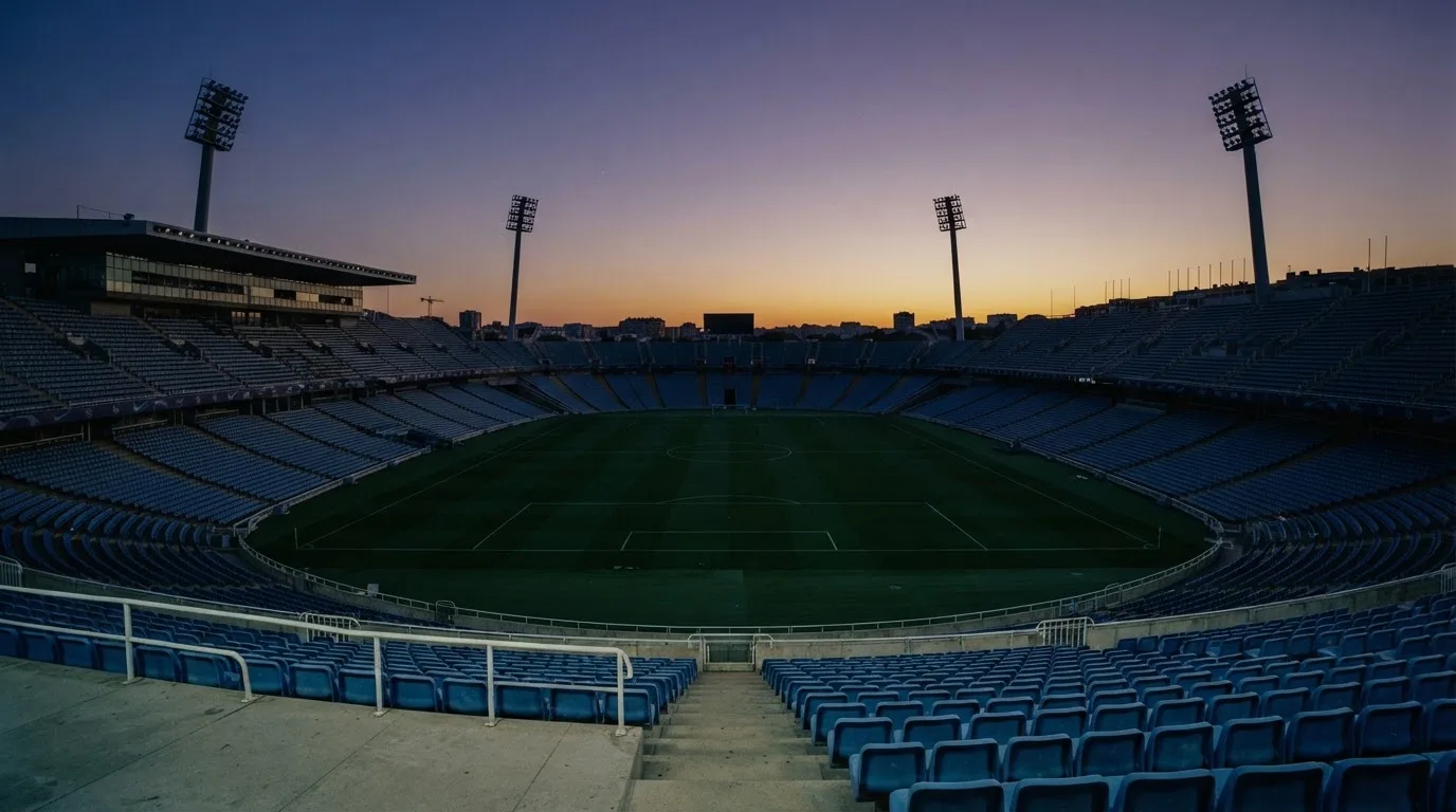 An empty football stadium with floodlight masts at dusk